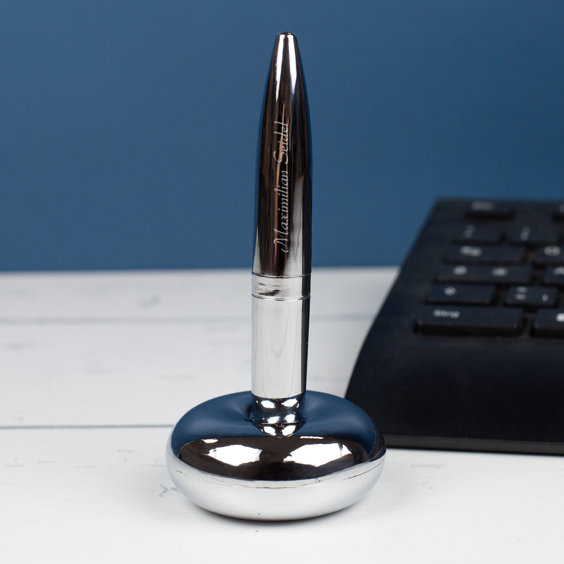 Magischer Kugelschreiber mit Namensgravur stehend in Ständer neben Tastatur