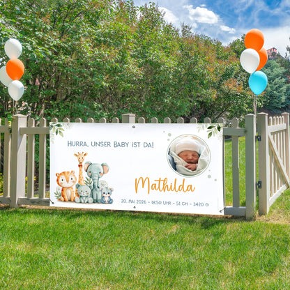 Personalisiertes Banner zur Geburt mit Tiermotiv und Babyfoto am Gartenzaun befestigt