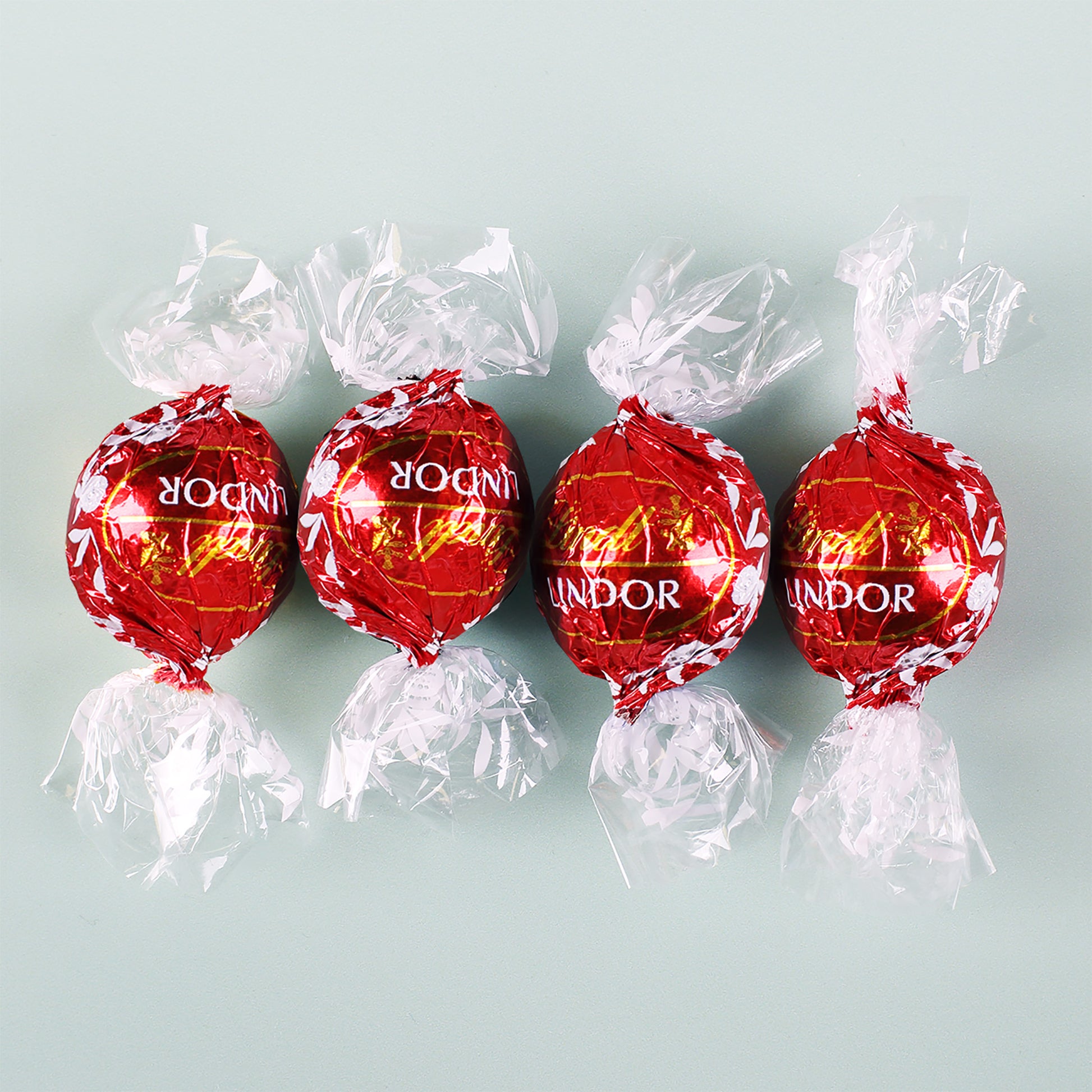 Vier Lindt Lindor Kugeln aus Vollmilch-Schokolade mit roter Verpackung
