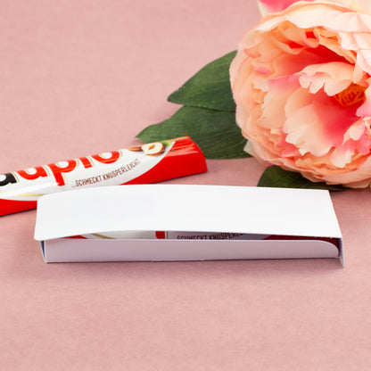 Geöffnete Geschenkverpackung für duplo Riegel mit Schokolade und Blume auf rosa Hintergrund