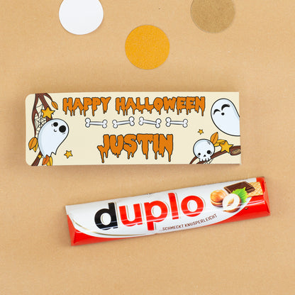 Duplo Riegel neben personalisierter Halloween-Geschenkverpackung mit Namen Justin, Geistern, Knochen und Totenkopf-Motiv