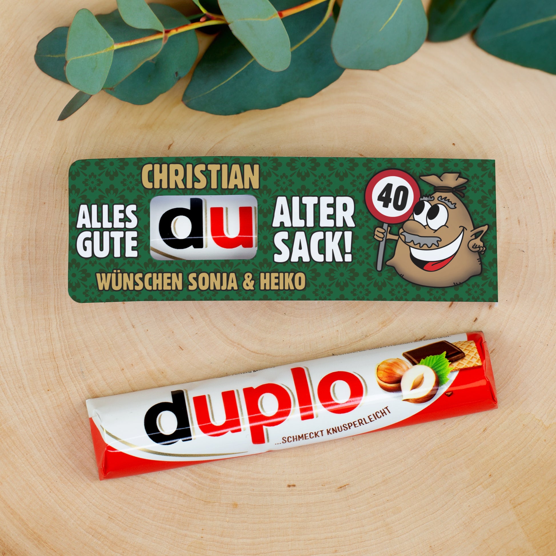duplo Schokoriegel mit personalisierter Geburtstagsbanderole dekorativ auf Holzuntergrund