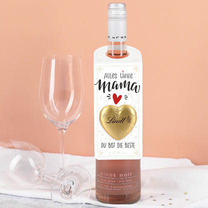 Großer Flaschenanhänger in Weiß mit goldenen Akzenten und dem Aufdruck „Alles Liebe Mama“, ergänzt durch ein goldfarbenes Lindt Schokoladenherz, an einer Flasche präsentiert.