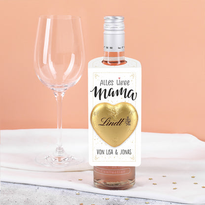 Nahaufnahme des aufgeklebt goldenen Lindt Schokoladenherzens auf dem kleinen weißen Flaschenanhänger.