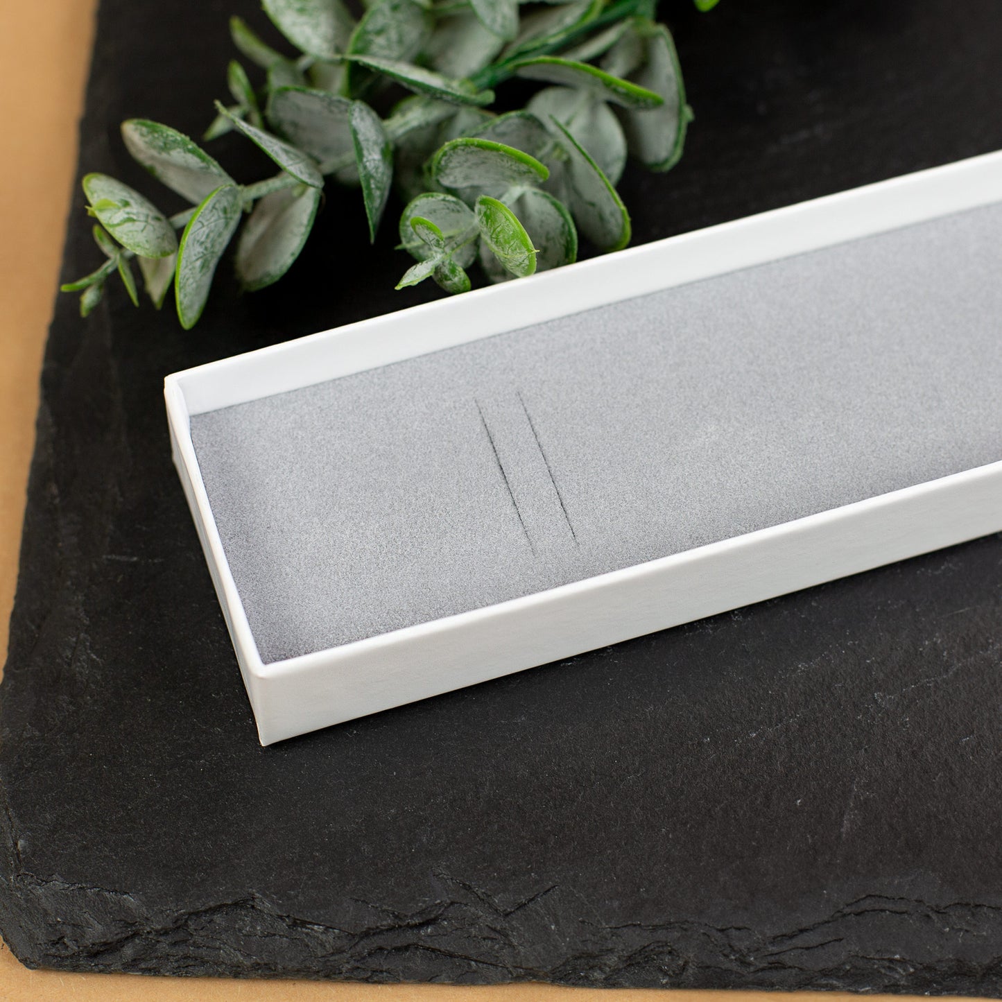 Innenansicht Schmuckverpackung mit grauem Schaumstoff auf dunklem Untergrund