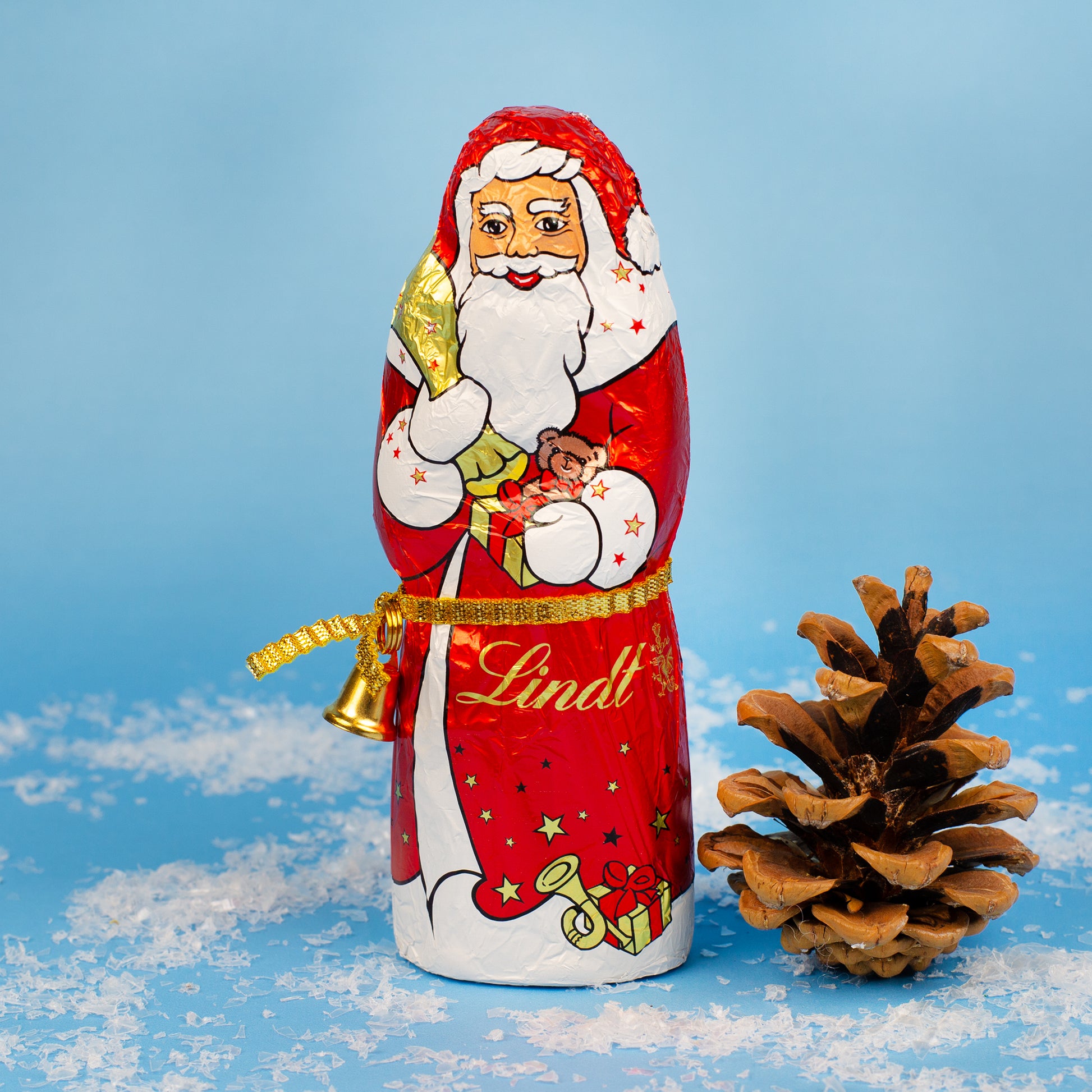 Einzelner Lindt Schokoladen-Weihnachtsmann mit Tannenzapfen und Kunstschnee als Dekoration