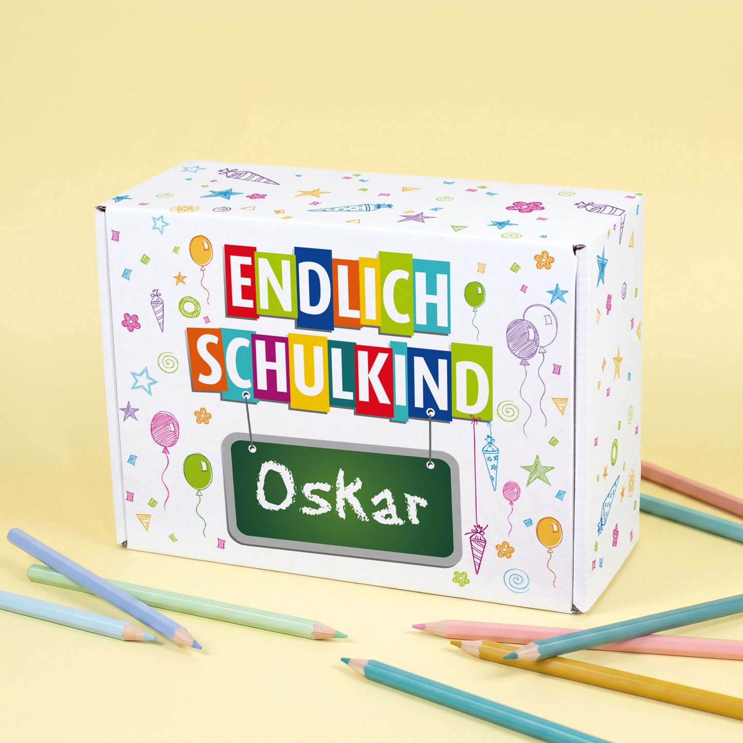 Kleine Pappbox mit bunten Einschulungs-Symbolen, Wuncshnamen und "Endlich Schulkind" Schriftzug