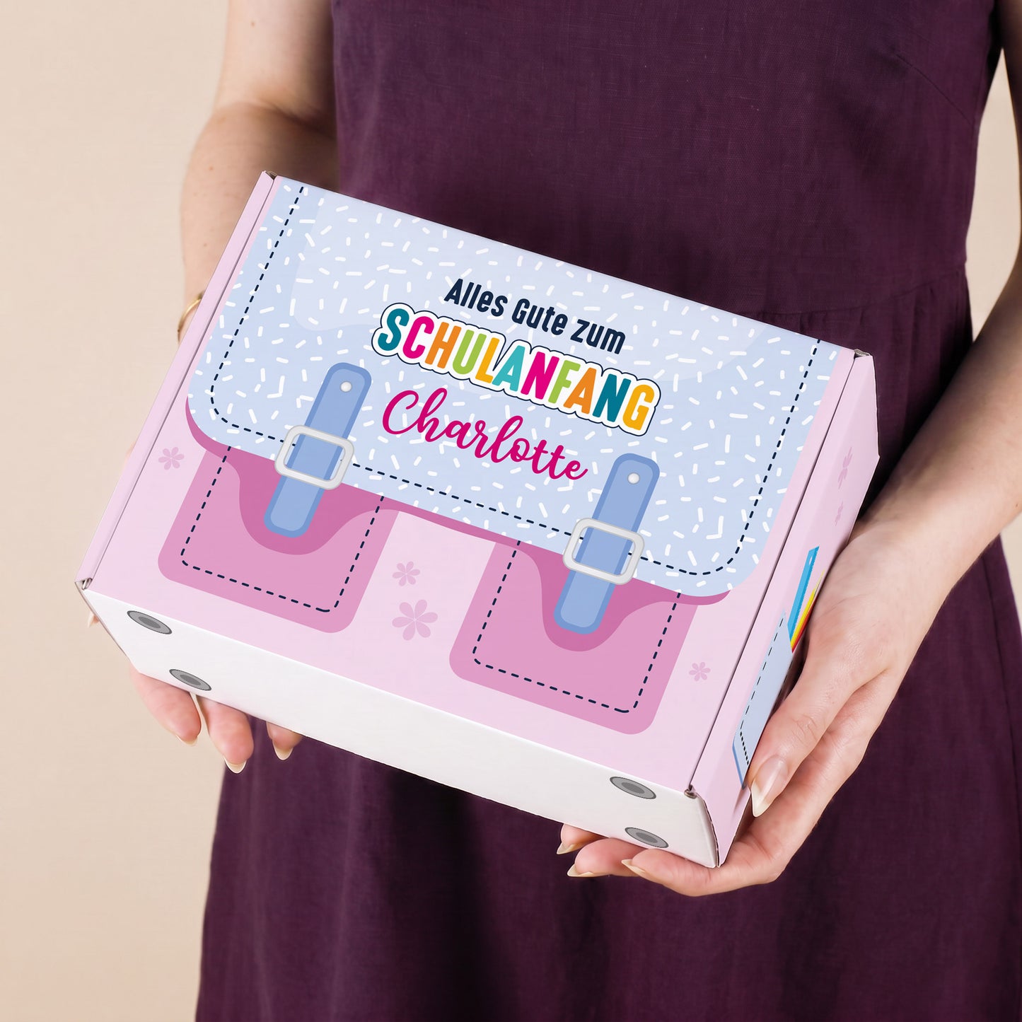 Kleine personalisierte Pappbox zur Einschulung in Rosa mit Schulranzen-Motiv und Name, von einer Person präsentiert