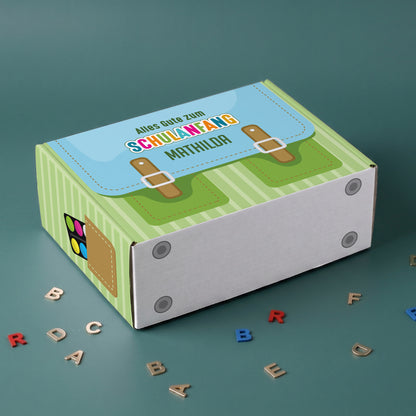 Kleine grüne Pappbox liegend mit Schulranzen Motiv und Wunschname bedruckt