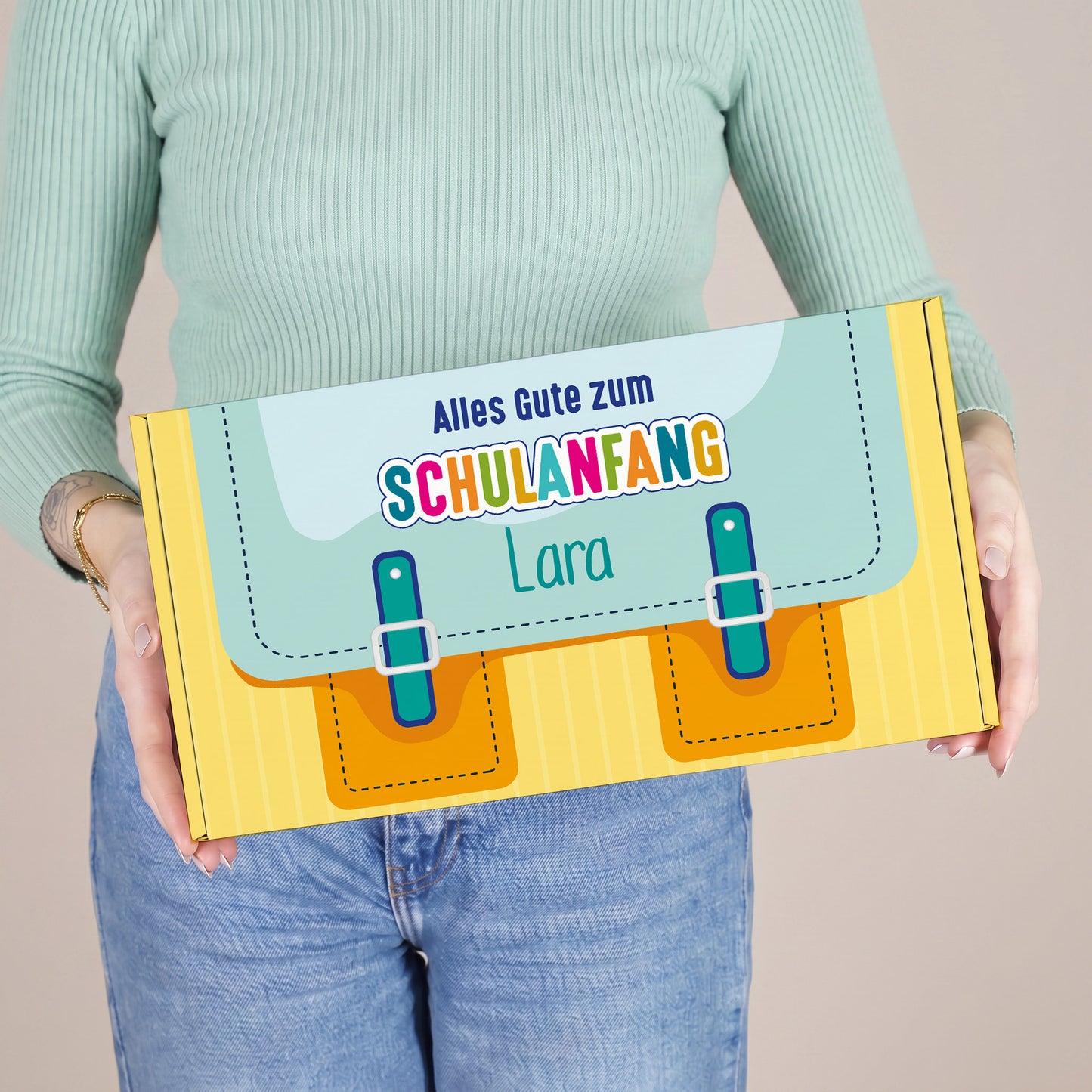 Mittlere gelbe Geschenkbox zum Schulanfang mit Name, von einer Person gehalten