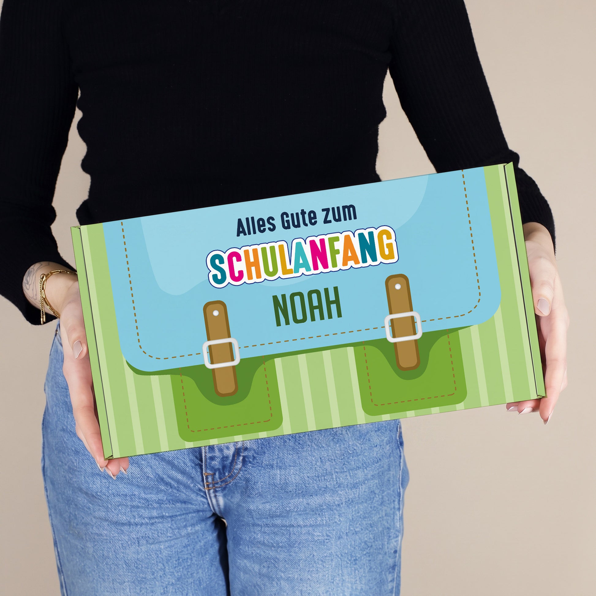 Mittlere grüne Geschenkverpackung zum Schulanfang mit Name, von einer Person gehalten