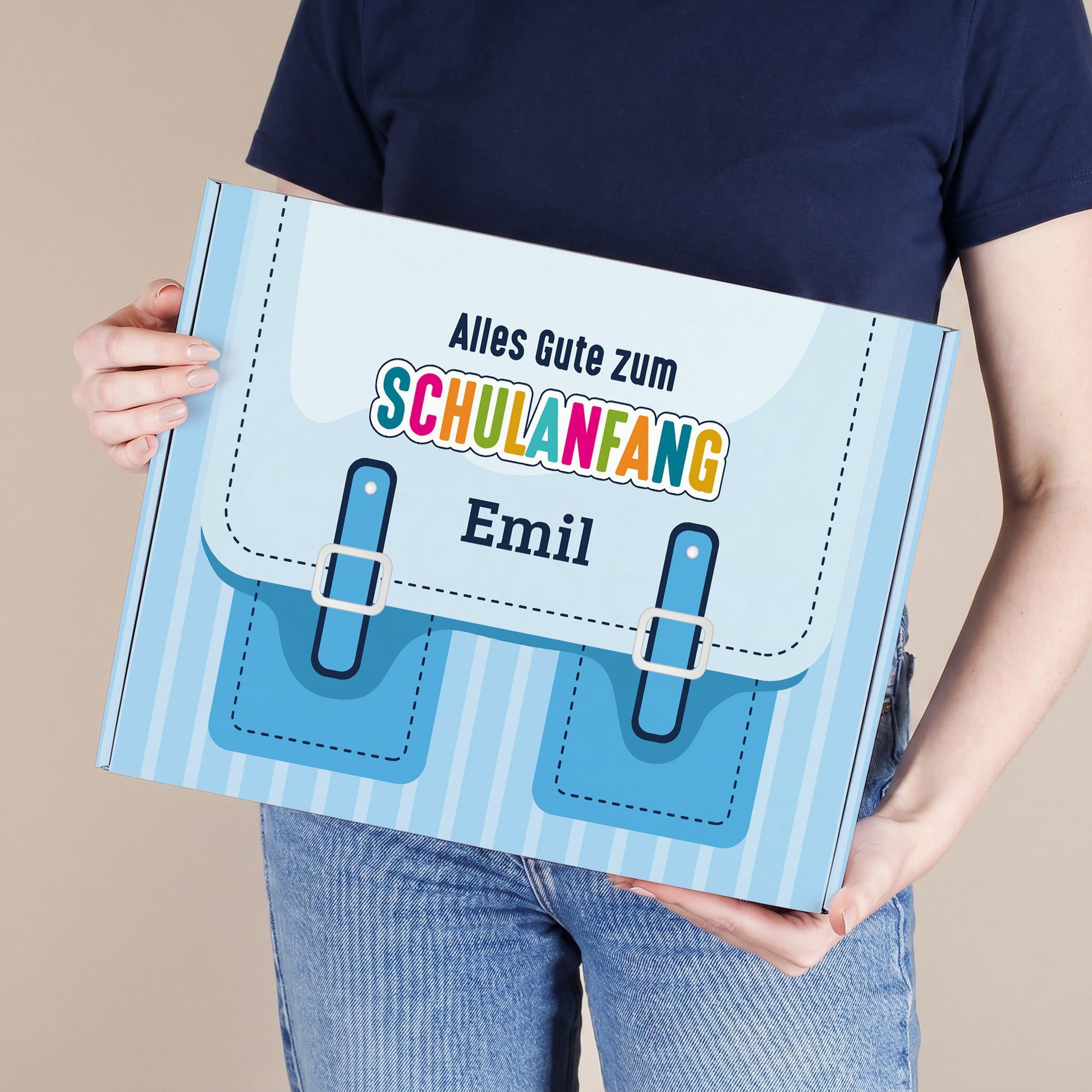 roße blaue Geschenkbox zum Schulanfang mit Wunschname, von einer Person gehalten