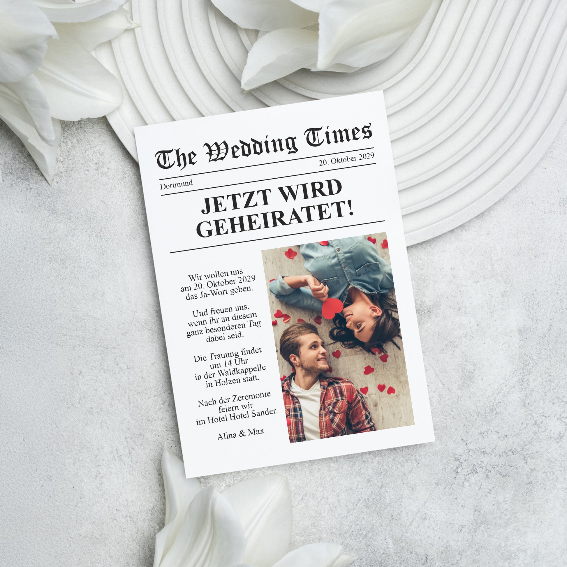 Zeitungsdesign Hochzeitseinladung „Jetzt wird geheiratet!“ mit Foto im Mittelpunkt auf heller Unterlage dekoriert