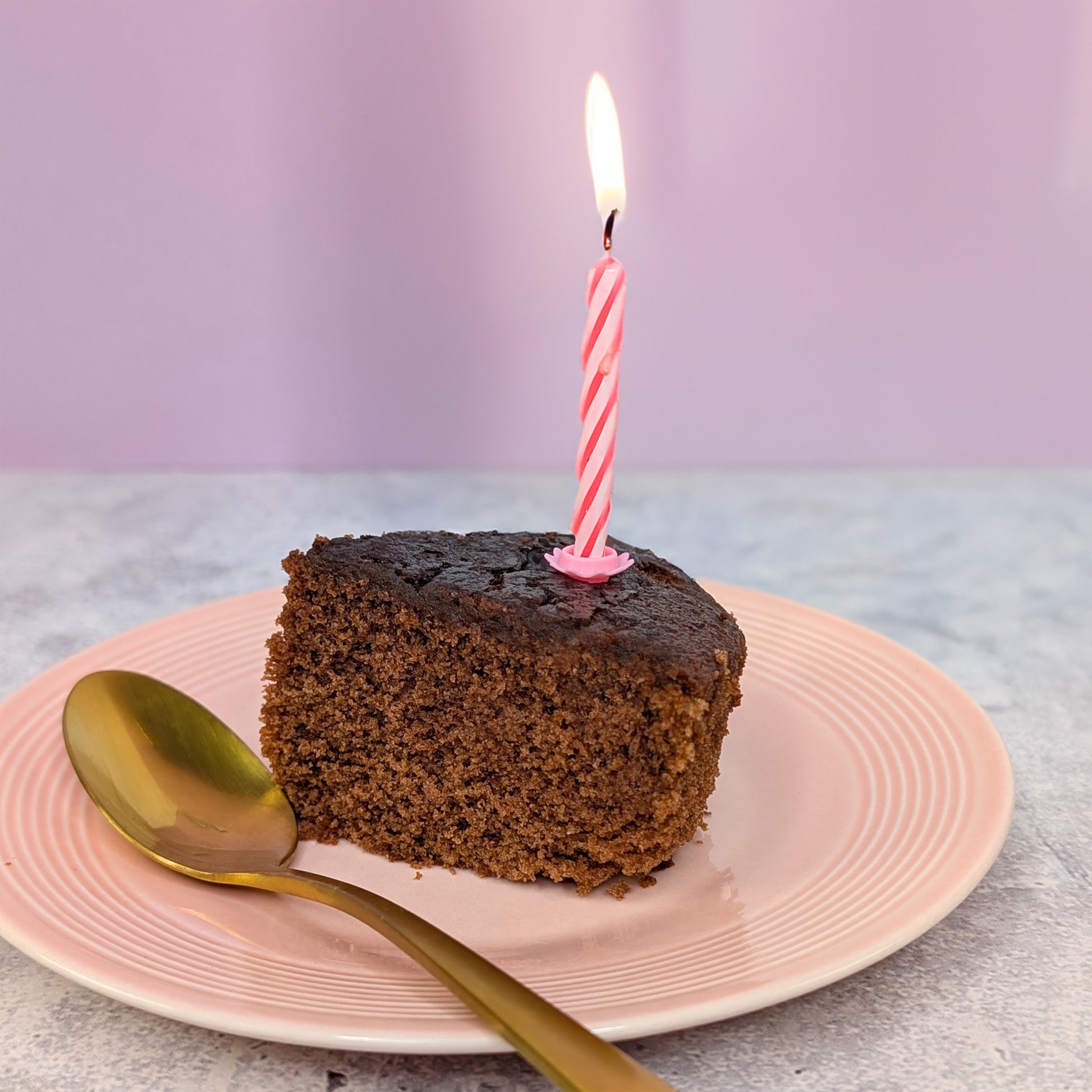 Stück Schokoladen Rührkuchen mit Kerze auf Teller als Serviervorschlag