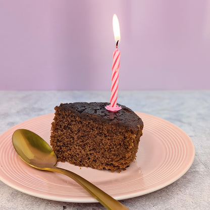 Stück Schokoladen Rührkuchen mit Kerze auf Teller als Serviervorschlag