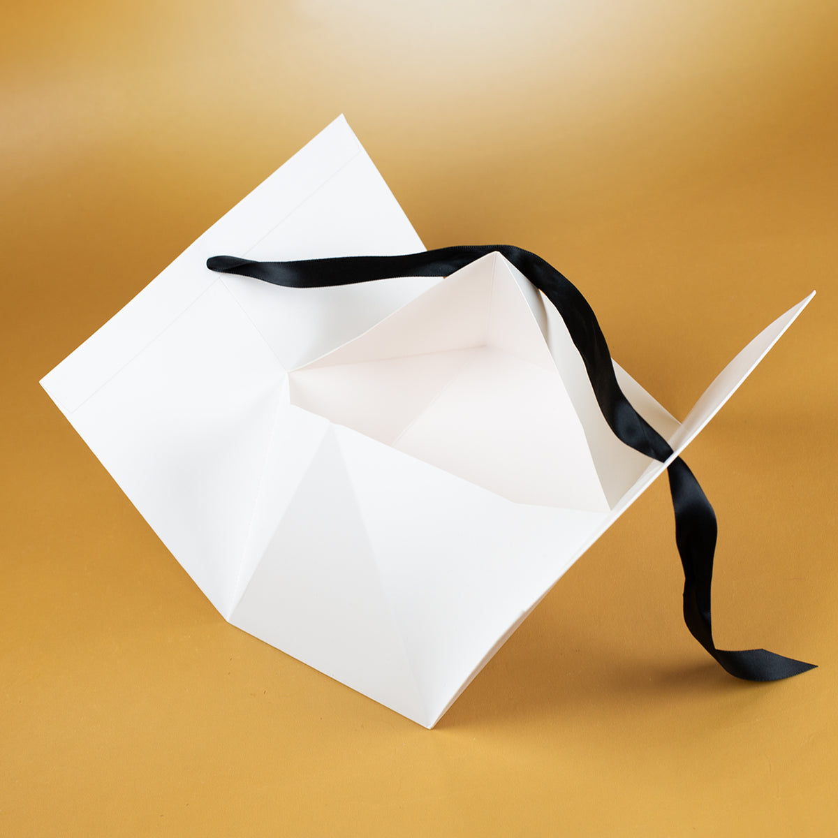 Geöffnete weiße Weihnachts-Geschenktasche mit schwarzem Satinband und großzügigem Innenraum zum Befüllen