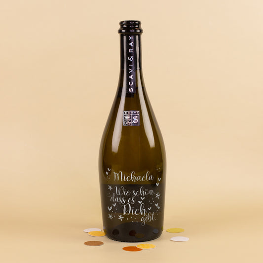 Personalisierte Scavi & Ray Prosecco-Flasche mit Gravur Michaela und Spruch Wie schön, dass es Dich gibt auf hellem Hintergrund