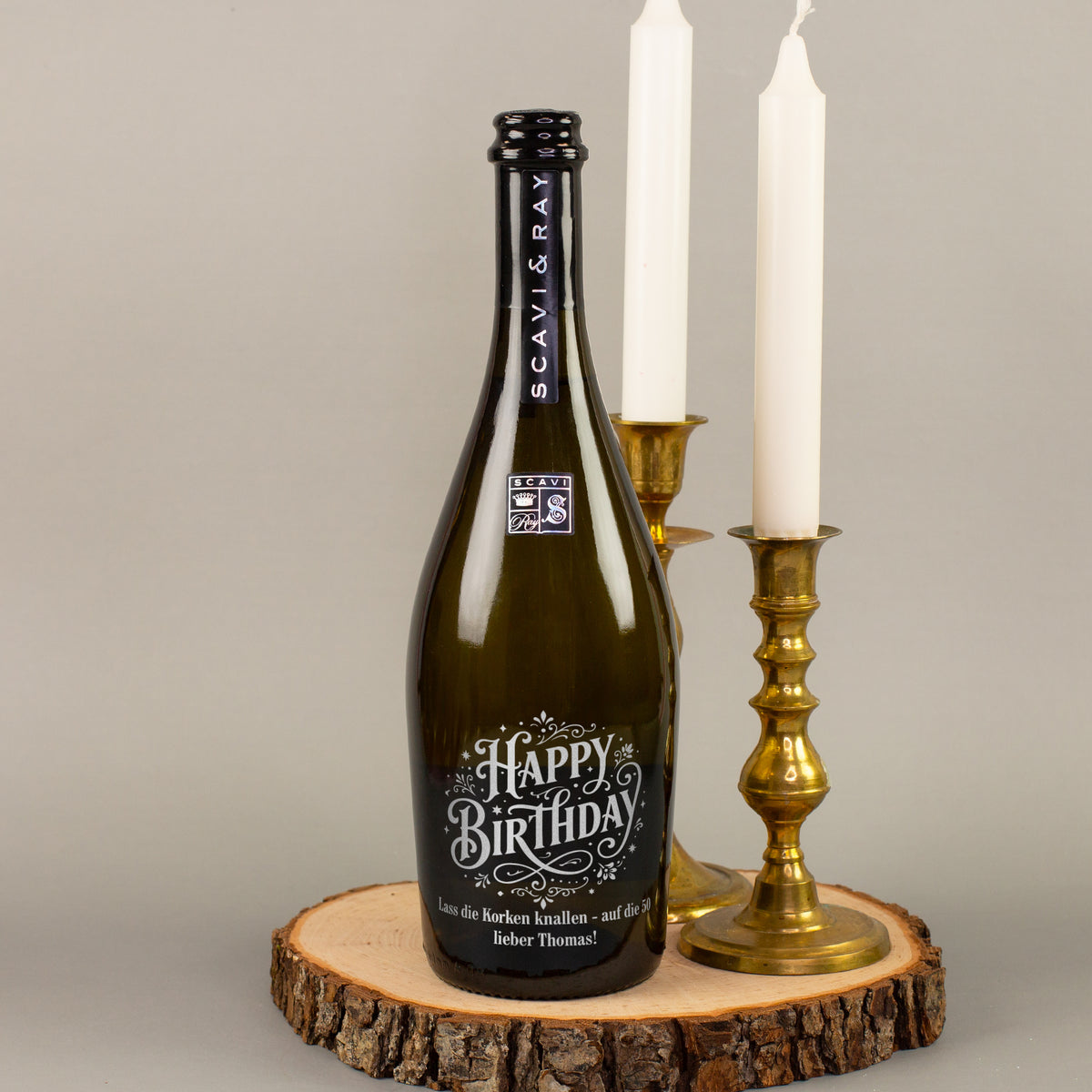 Personalisierte Scavi & Ray Prosecco-Flasche mit Happy-Birthday-Gravur und Wunschtext „Lass die Korken knallen – auf die 50 lieber Thomas“ neben Kerzen