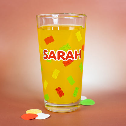 Personalisierbares HARIBO Glas mit bunten Gummibärchenmotiven und großem weißen Namensdruck „Sarah“, gefüllt mit gelber Flüssigkeit.