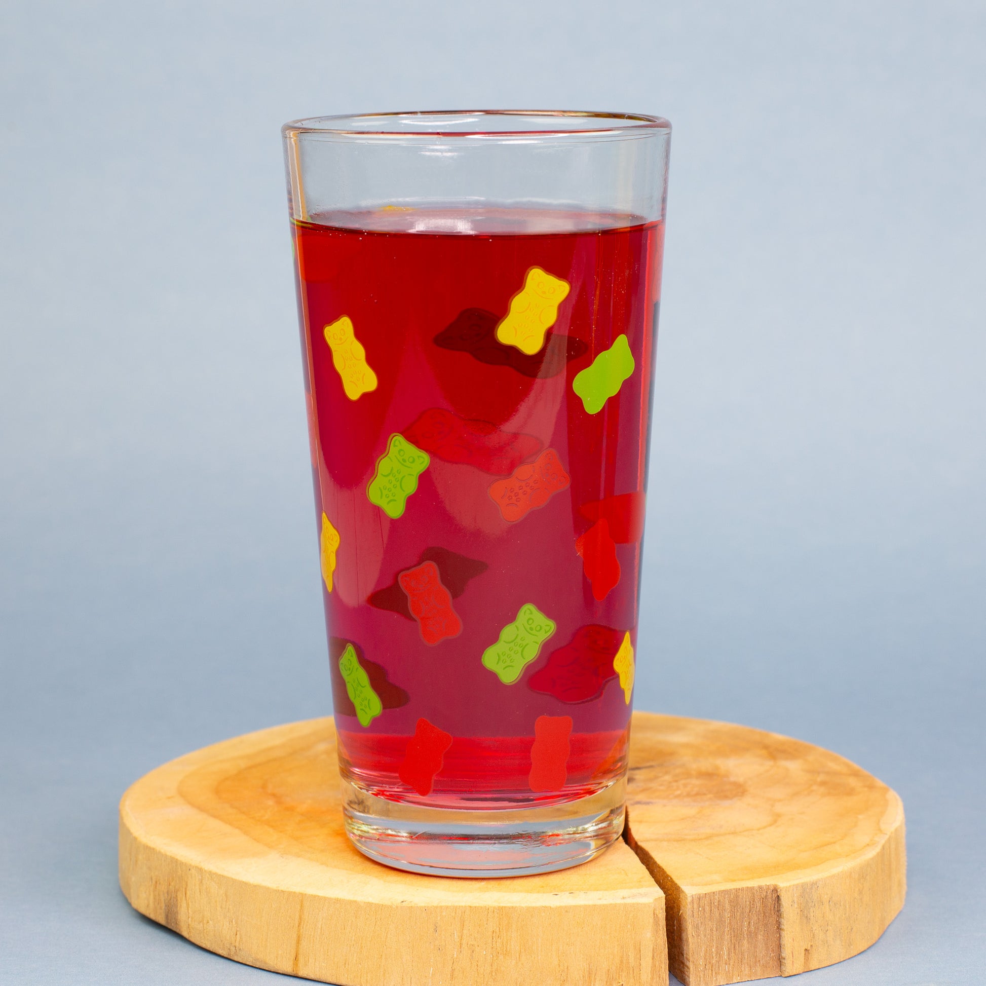 HARIBO Trinkglas mit buntem Gummibärchen Motiv, gefüllt mit gelbem Getränk auf warmem Hintergrund