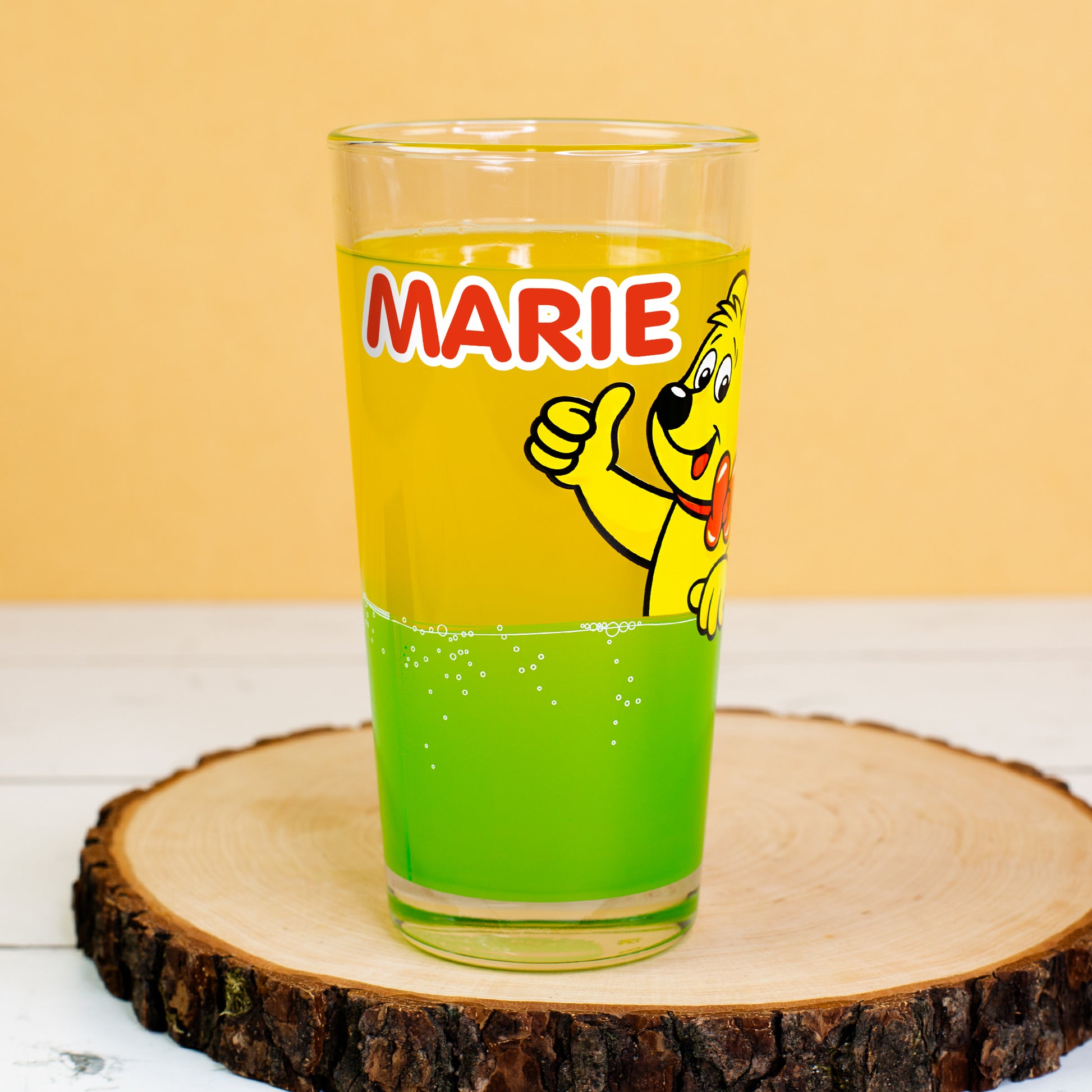 HARIBO Trinkglas mit Name Marie und grünem Limonadendesign, dekorativ auf Holzuntersetzer präsentiert.