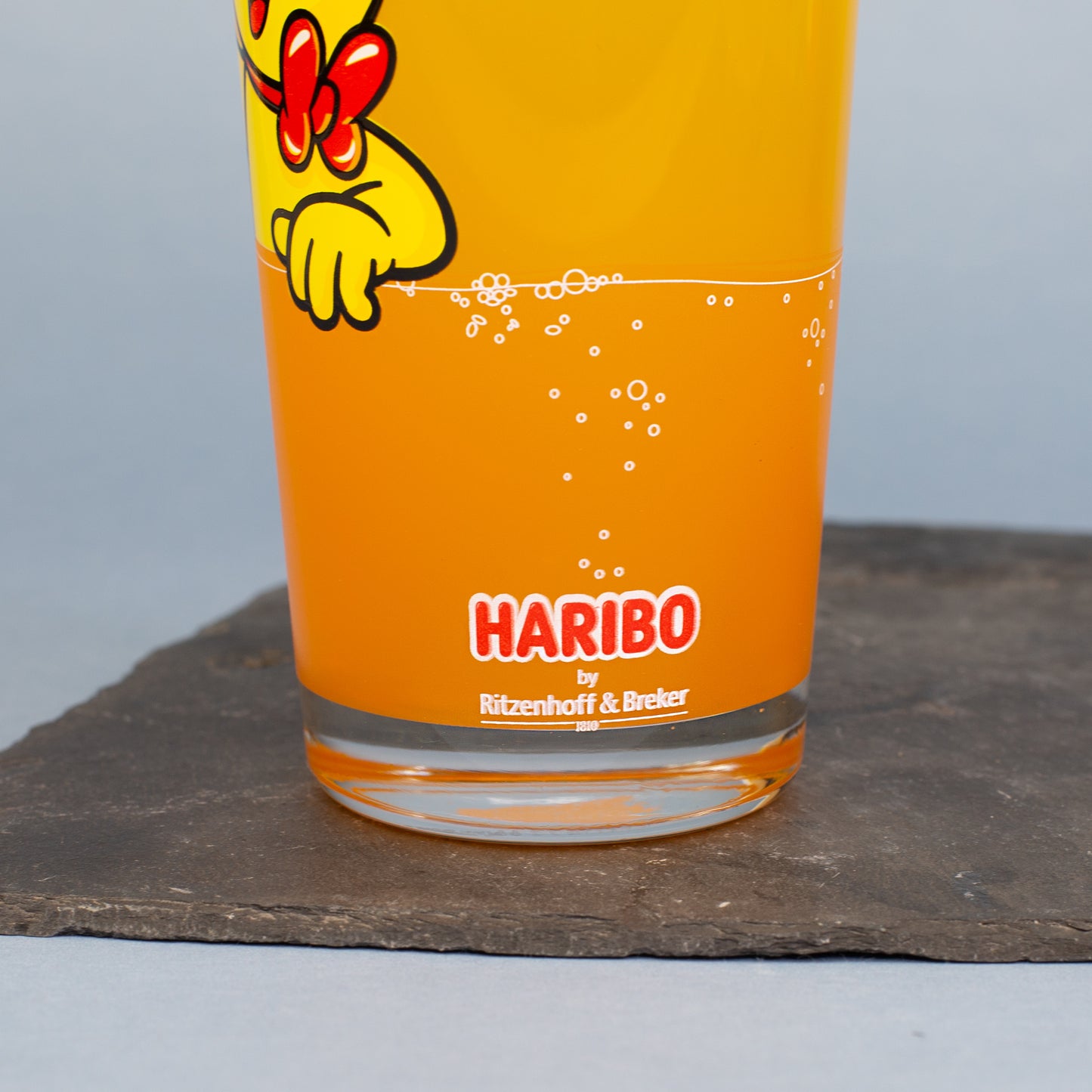 Detailansicht des HARIBO Logos am unteren Rand des Glases im orangen Limonadenbereich.