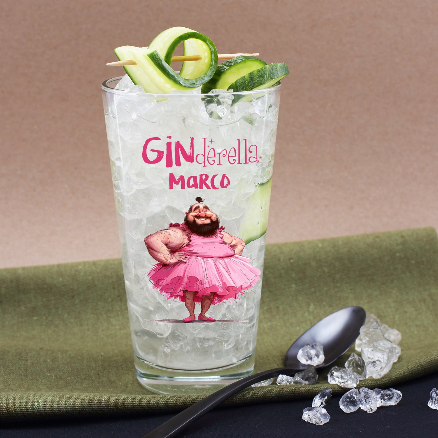Personalisiertes Trinkglas mit Ginderella Motiv und Name Marco, Eiswürfeln, Gurke und Cocktaildeko auf grünem Tuch