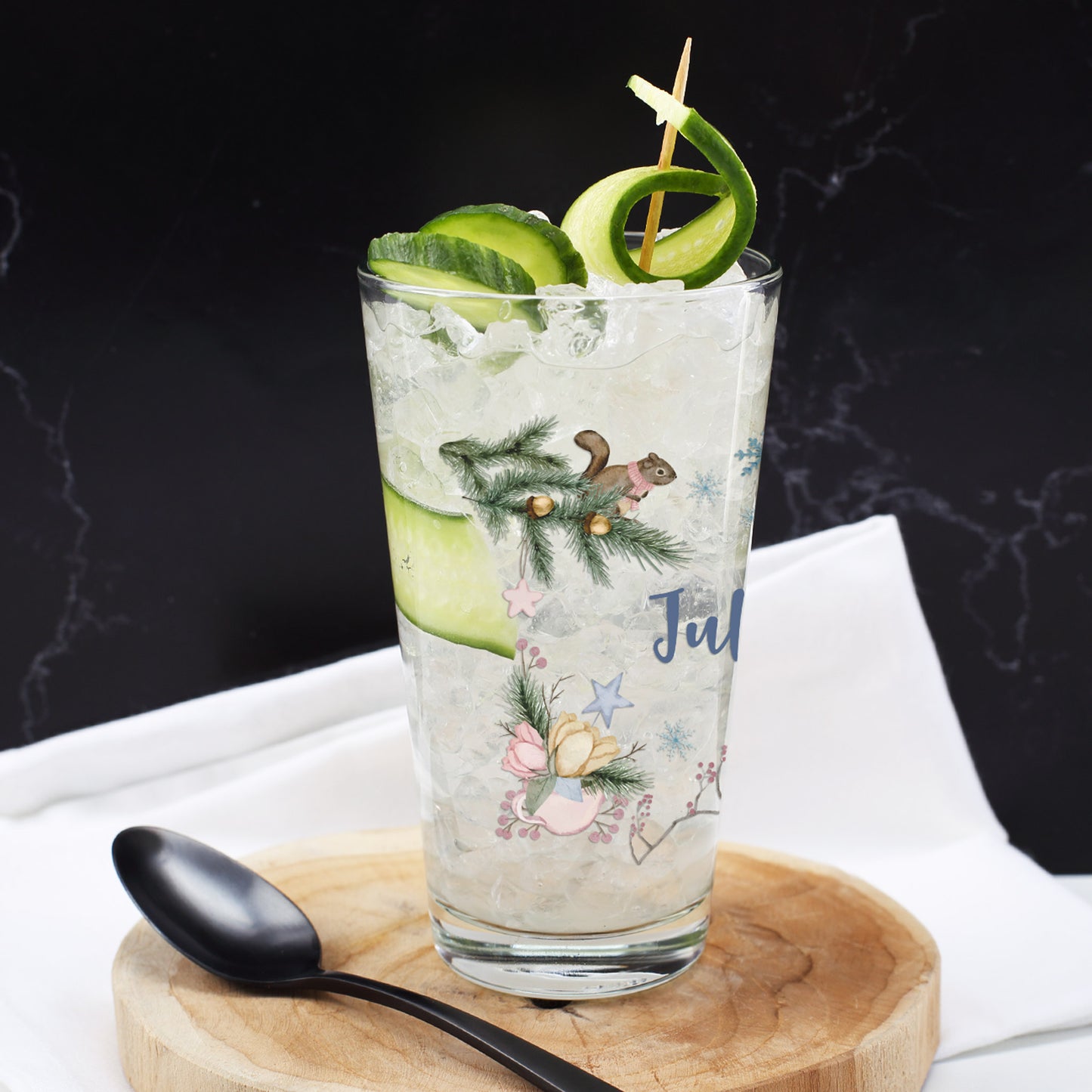 Trinkglas mit winterlichem Motiv und Namensaufdruck „Julius“, gefüllt mit Crushed Ice und Gurkenspirale