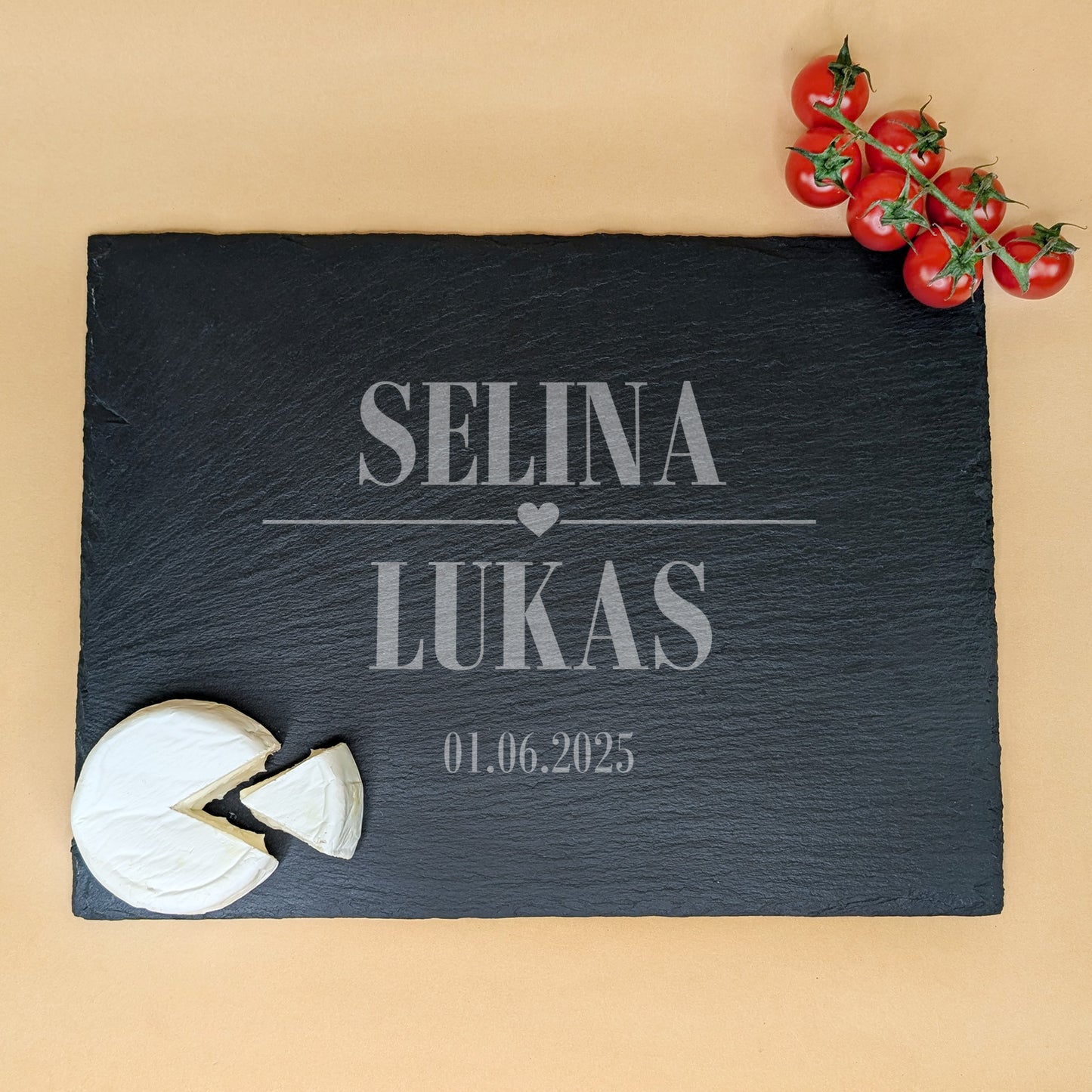 Schieferplatte mit Gravur „SELINA ♥ LUKAS“ und Datum 01.06.2025, dekoriert mit Tomatenrispe und rundem Weichkäse