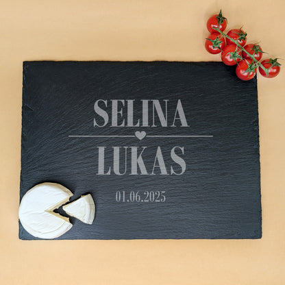 Schieferplatte mit Gravur „SELINA ♥ LUKAS“ und Datum 01.06.2025, dekoriert mit Tomatenrispe und rundem Weichkäse