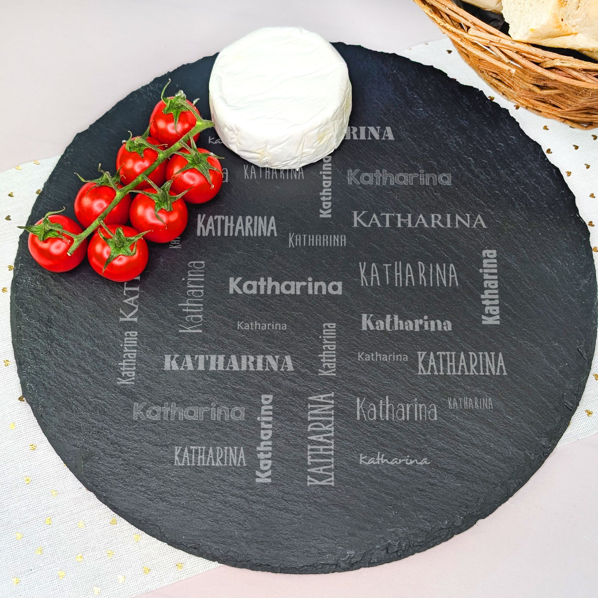 Runde Schieferplatte mit Gravur „Katharina“, dekoriert mit Camembert und Tomaten auf hellem Tischtuch
