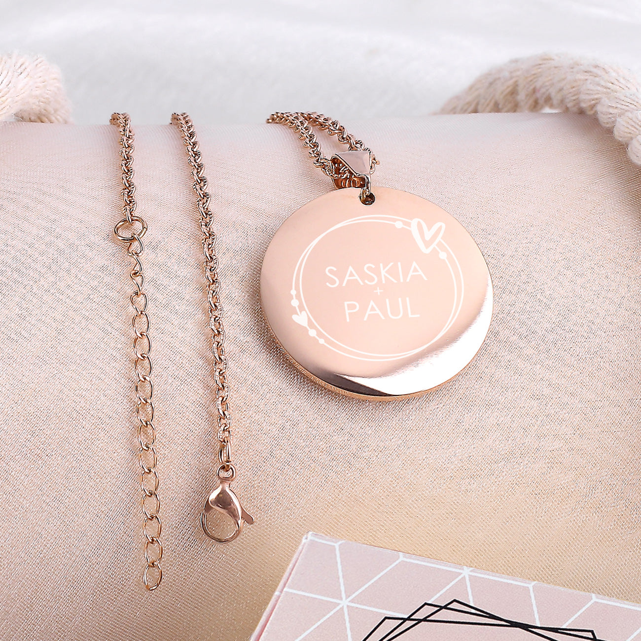 Gravierte Namenskette mit Herzen - in Roségold auf rosa Untergrund