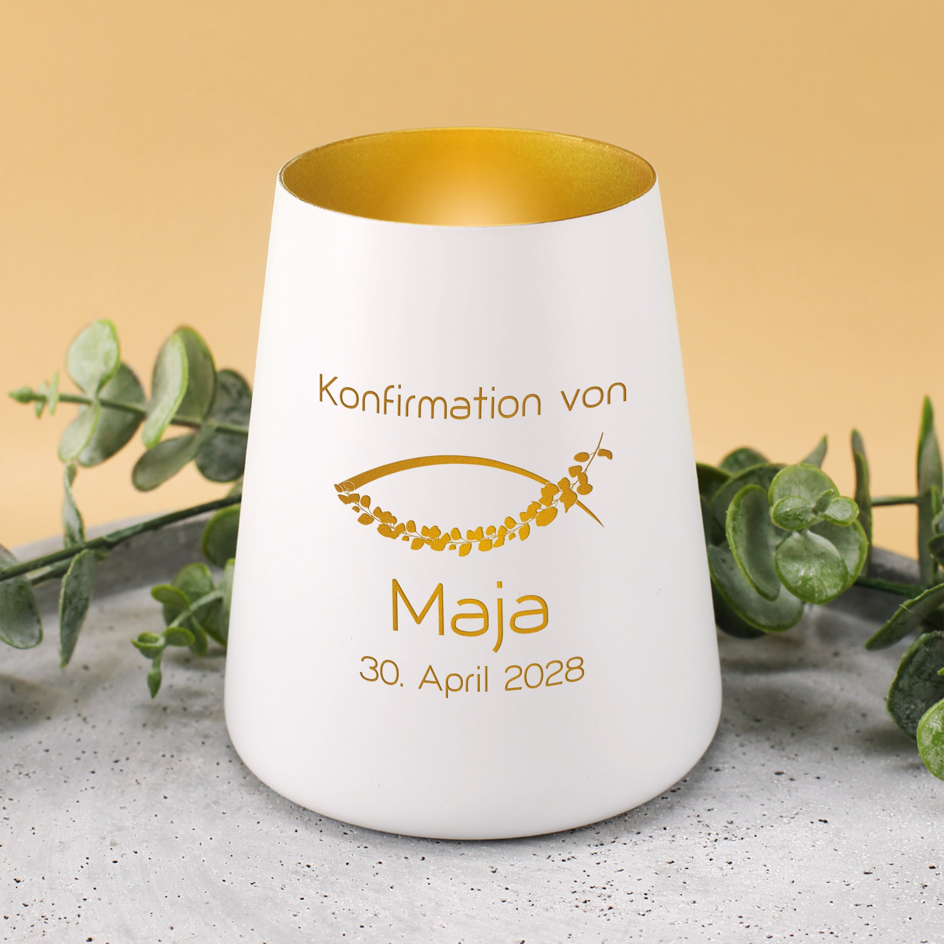 Weißes Windlicht zur Konfirmation mit goldfarbenem Ichthys-Fischmotiv, Name Maja und Datum, dekoriert mit Eukalyptus