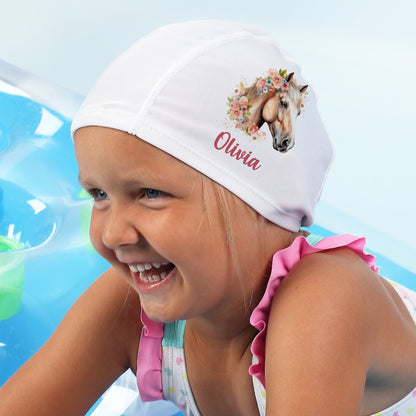 Mädchen lacht mit Badekappe Pferdemotiv und Name „Olivia“