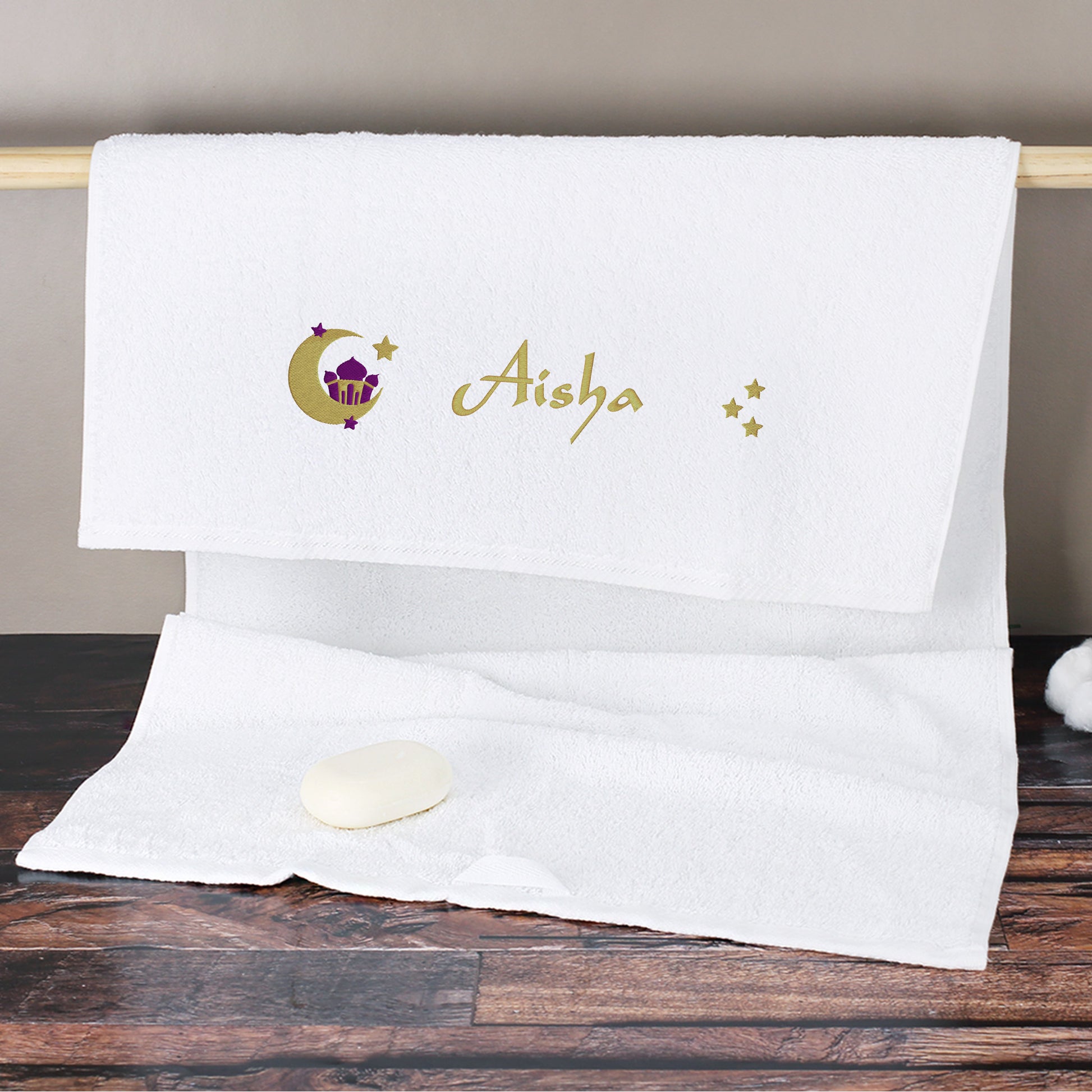 Weißes Handtuch mit orientalischem Motiv und Name Aisha bestickt am Handtuchhalter im Badezimmer mit Seife
