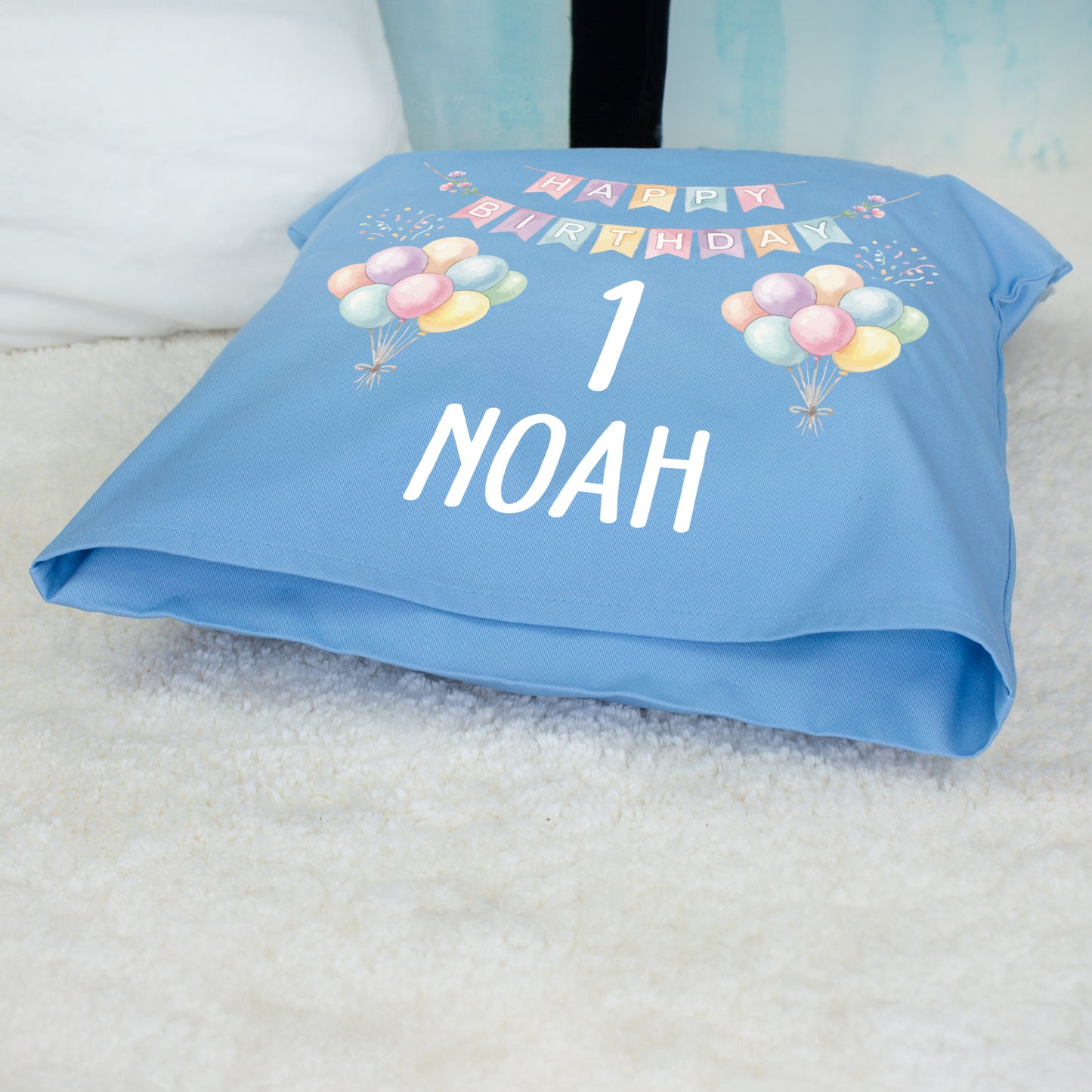 Blaues personalisiertes Geburtstagskissen mit Ballons, Zahl 1 und Name Noah liegend fotografiert