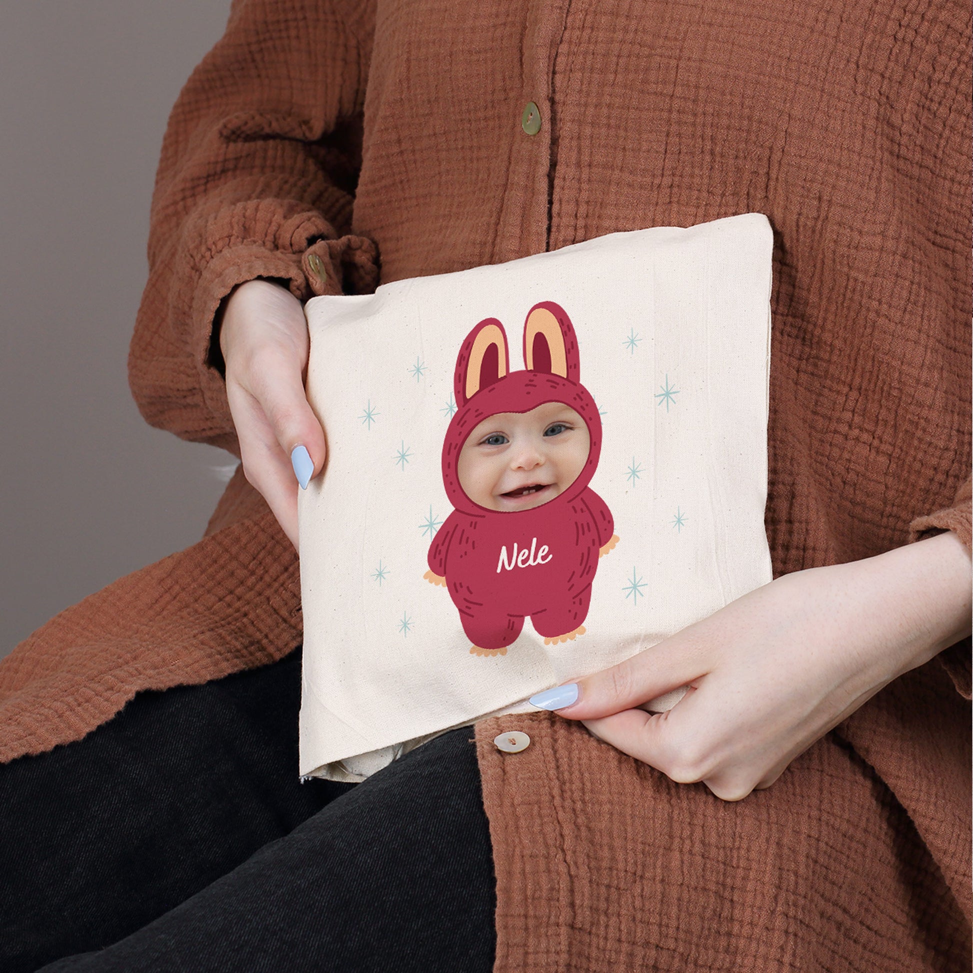 Rotes Kirschkernkissen mit Monster-Design, personalisiert mit Foto und Name „Nele“, in Händen gehalten