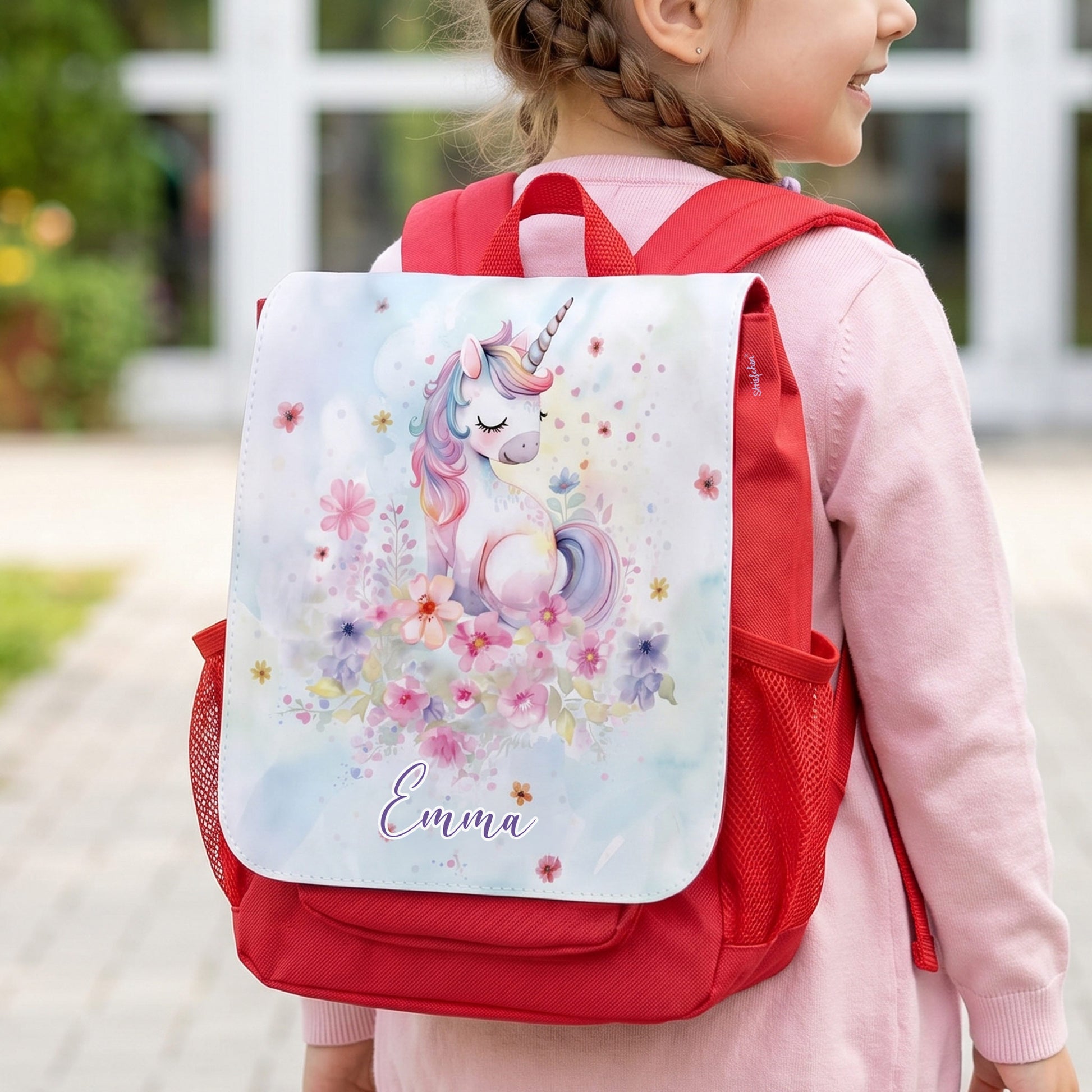 Mädchen trägt roten Kindergartenrucksack mit Einhornmotiv, Blumen und personalisiertem Namen Emma