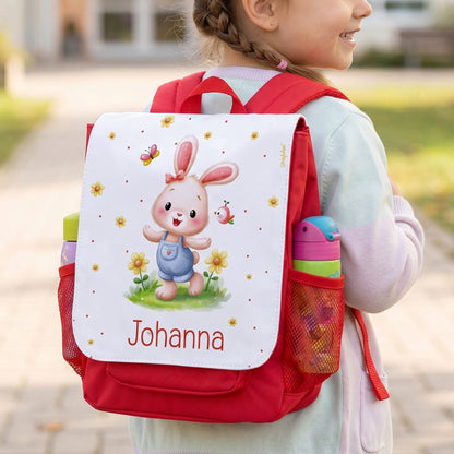 Mädchen trägt roten Kindergartenrucksack mit Hasenmotiv, Blumen, Trinkflasche und Name Johanna
