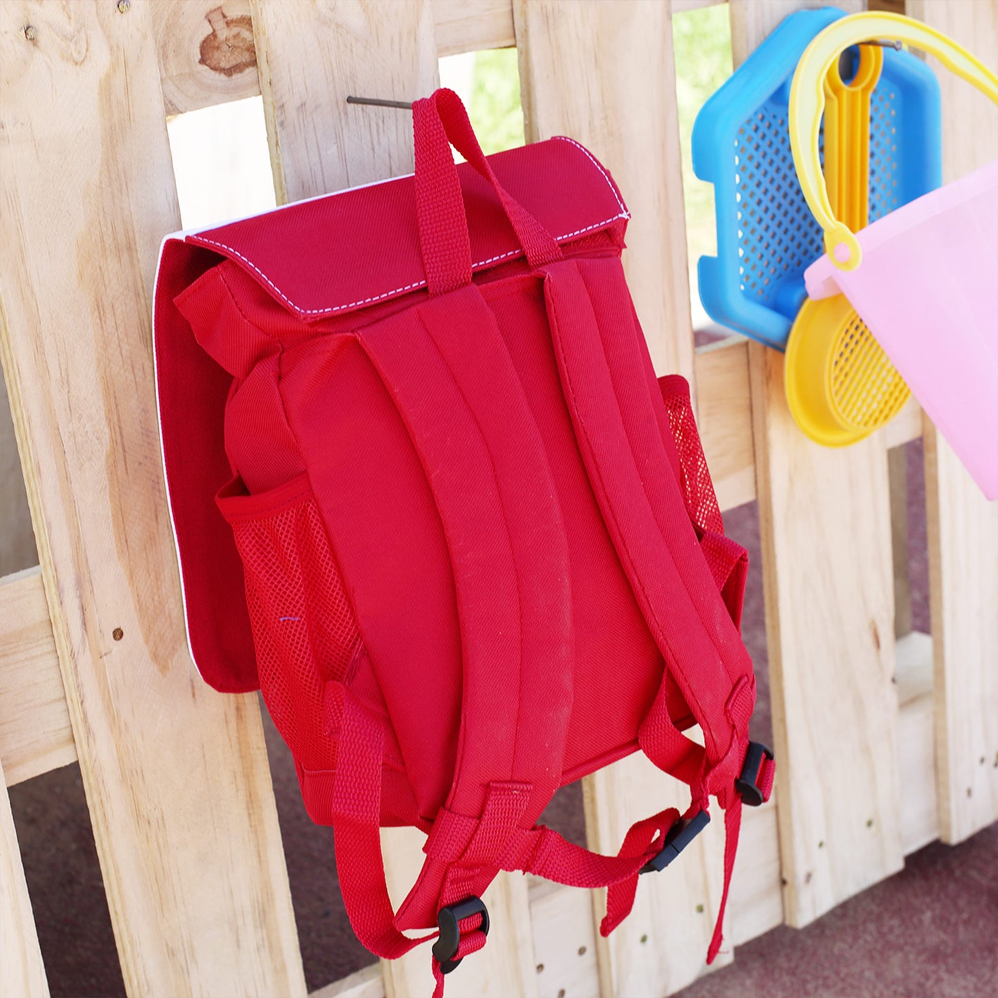 Rückseite des roten Kindergartenrucksacks mit gepolsterten Trägern, Netzfächern und Klettverschluss