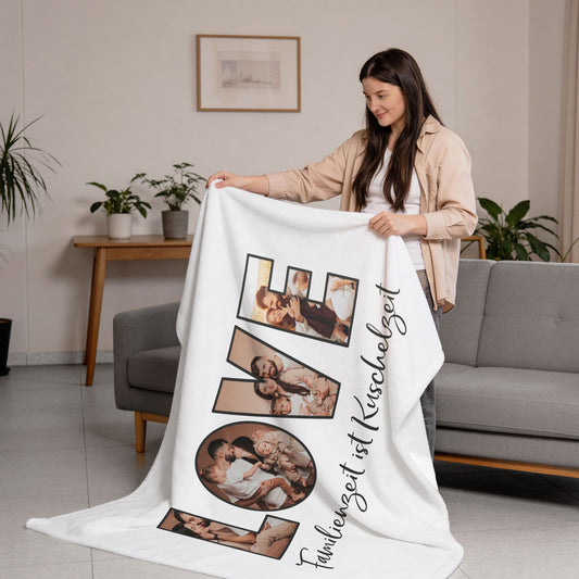 Fotodecke XXL mit LOVE Schriftzug aus vier Bildern und Spruch „Familienzeit ist Kuschelzeit“, gehalten von einer Frau im Wohnzimmer
