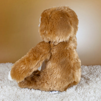 Rückansicht des braunen Faultier-Kuscheltiers mit weichem Plüschfell auf Teppich.