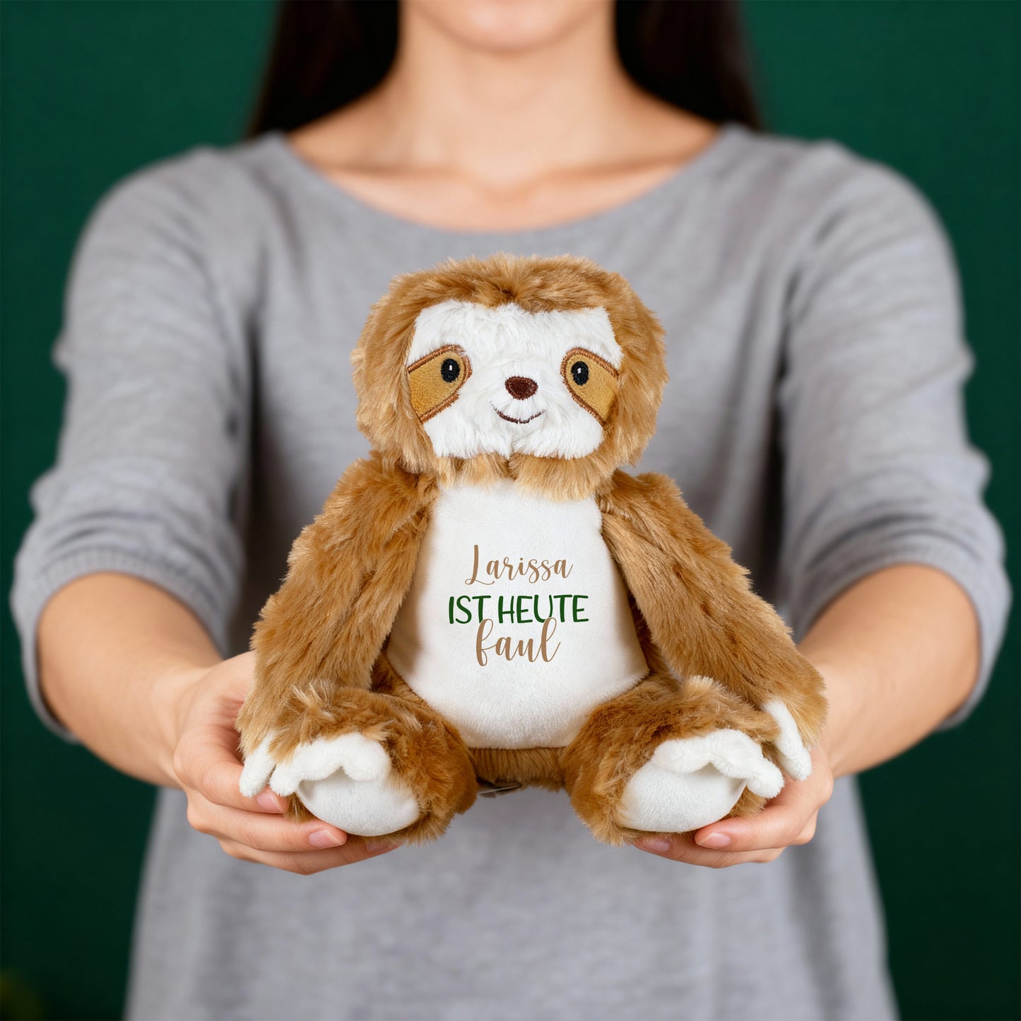 Frau hält personalisiertes Kuscheltier Faultier mit Spruch „ist heute faul“ in den Händen.