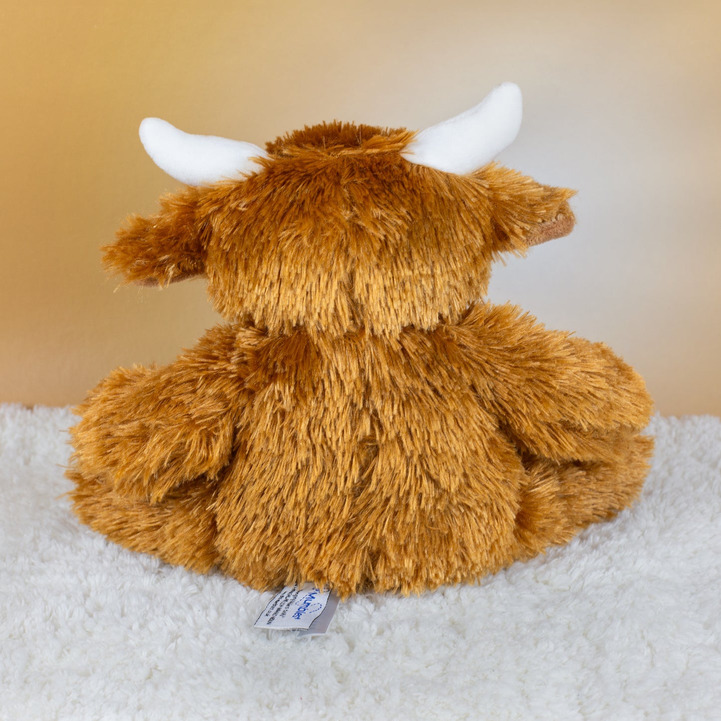 Rückansicht der plüschigen Kuscheltier-Kuh mit flauschigem braunen Fell und weißen Hörnern.