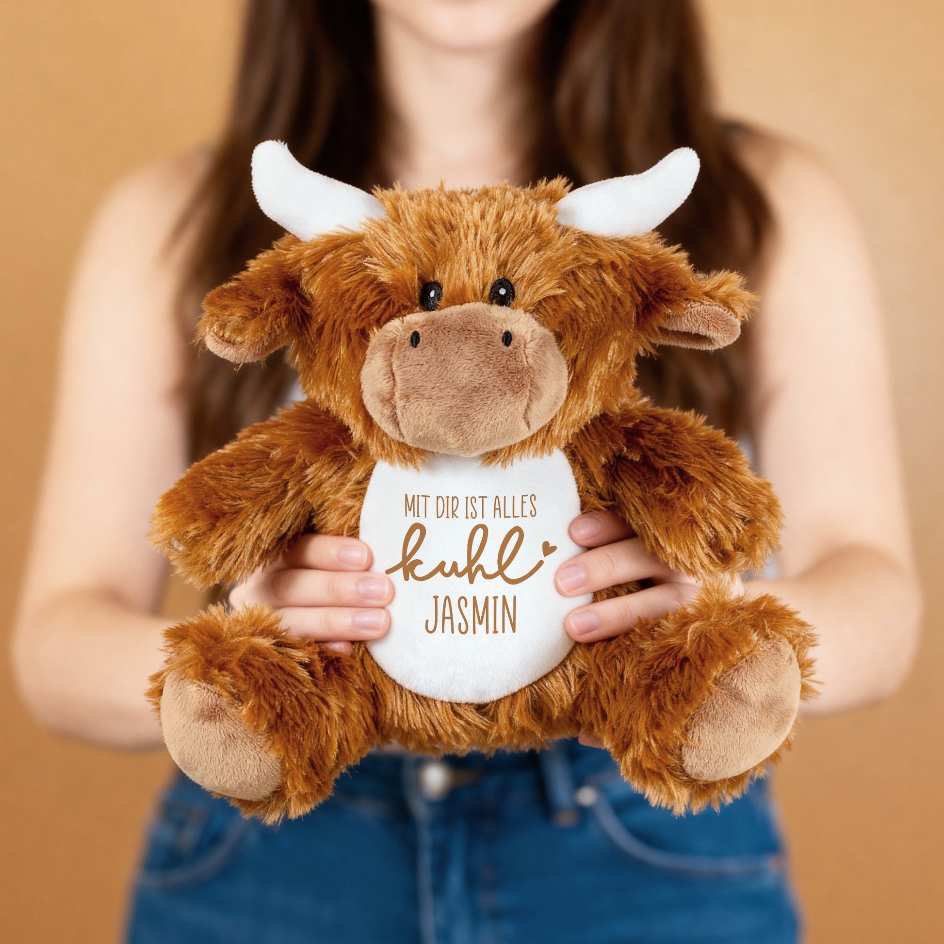 Frau hält personalisierte Kuscheltier-Kuh mit Spruch „Mit dir ist alles kuhl“ und Name Jasmin.