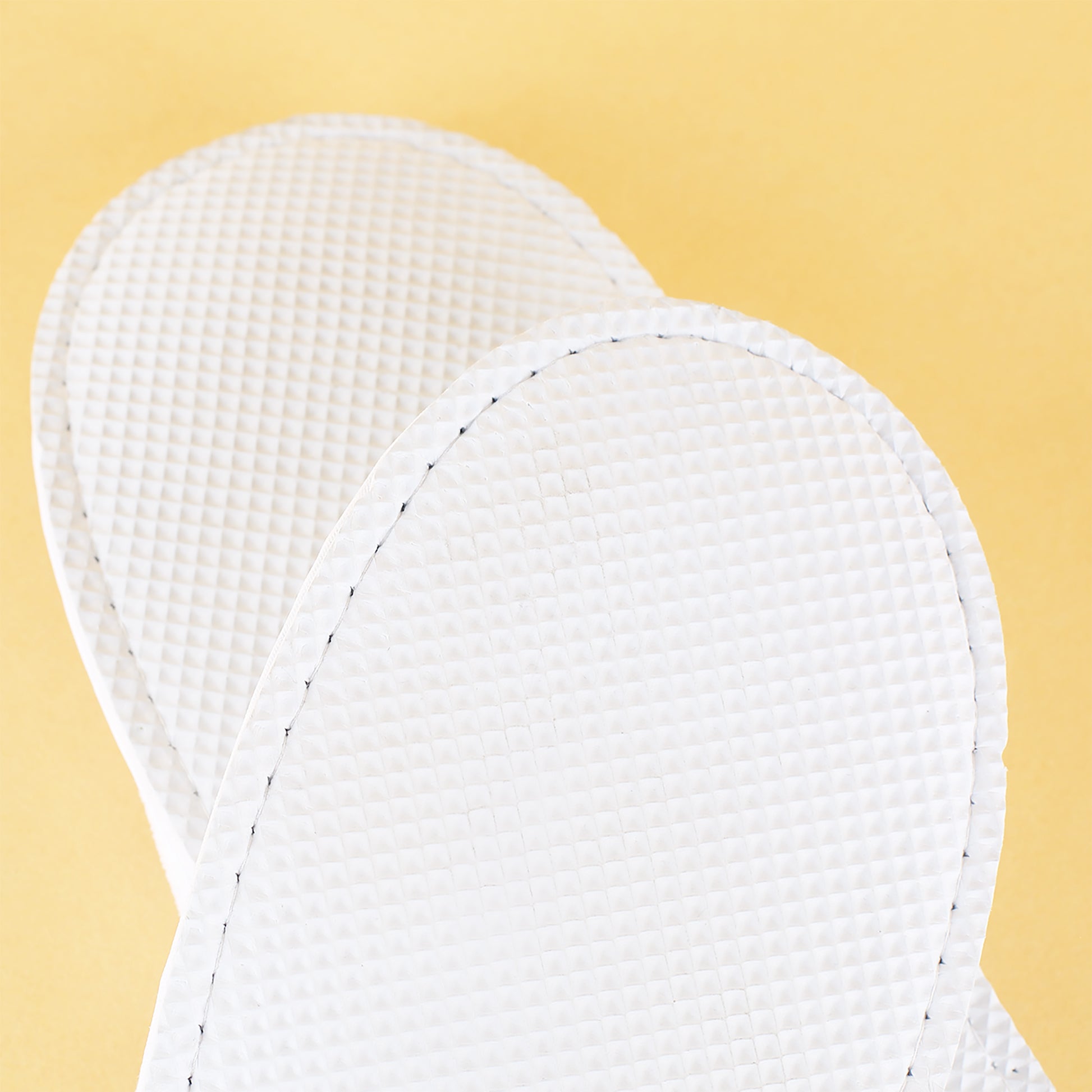 Detailansicht der weißen Pantoffeln mit strukturierter Sohle – rutschfest und wasserdicht