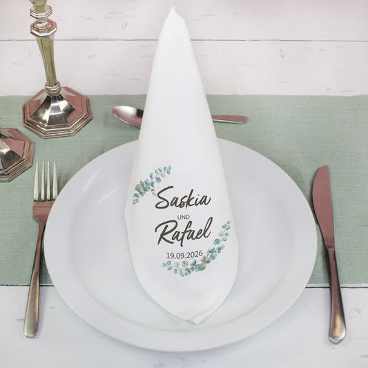 Personalisierte Stoffserviette mit Namen im Eukalyptus Design gefaltet auf gedecktem Hochzeitstisch