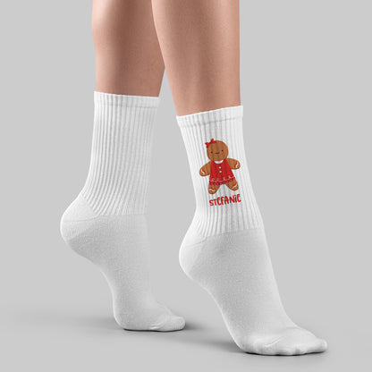 Bedruckter Weihnachtssocken mit Lebkuchenfrau und Namen, getragen an einem Bein vor grauem Hintergrund.