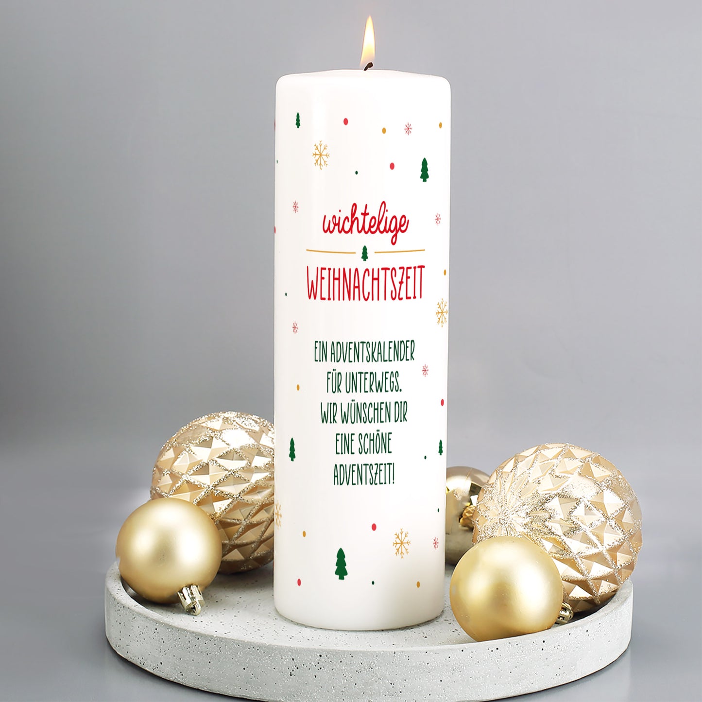 Brennende Adventskalender-Kerze mit Wichtelmotiv und personalisiertem Text, dekoriert mit goldenen Christbaumkugeln