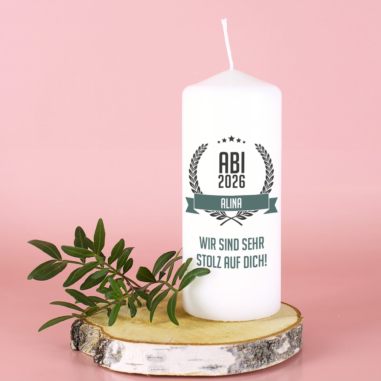 Abitur Kerze mit Name und Glückwunschtext auf Baumscheibe vor rosa Hintergrund